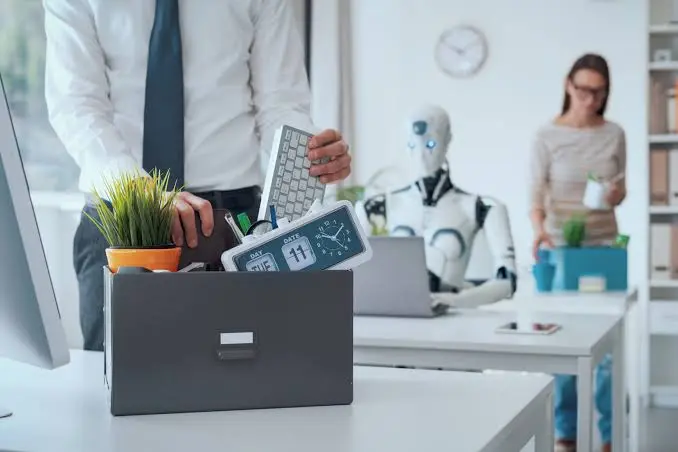 Persona guardando sus pertenencias de oficina mientras un robot trabaja de fondo, representando la automatización de tareas administrativas repetitivas