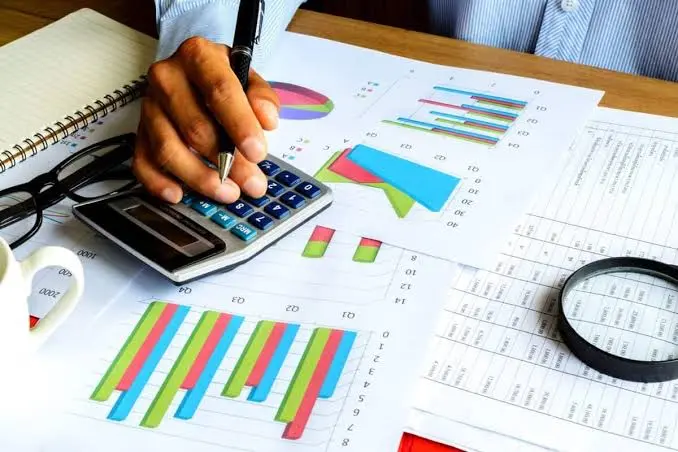 Persona analizando gráficos financieros con calculadora, representando el acceso democratizado a herramientas de análisis de alta gama