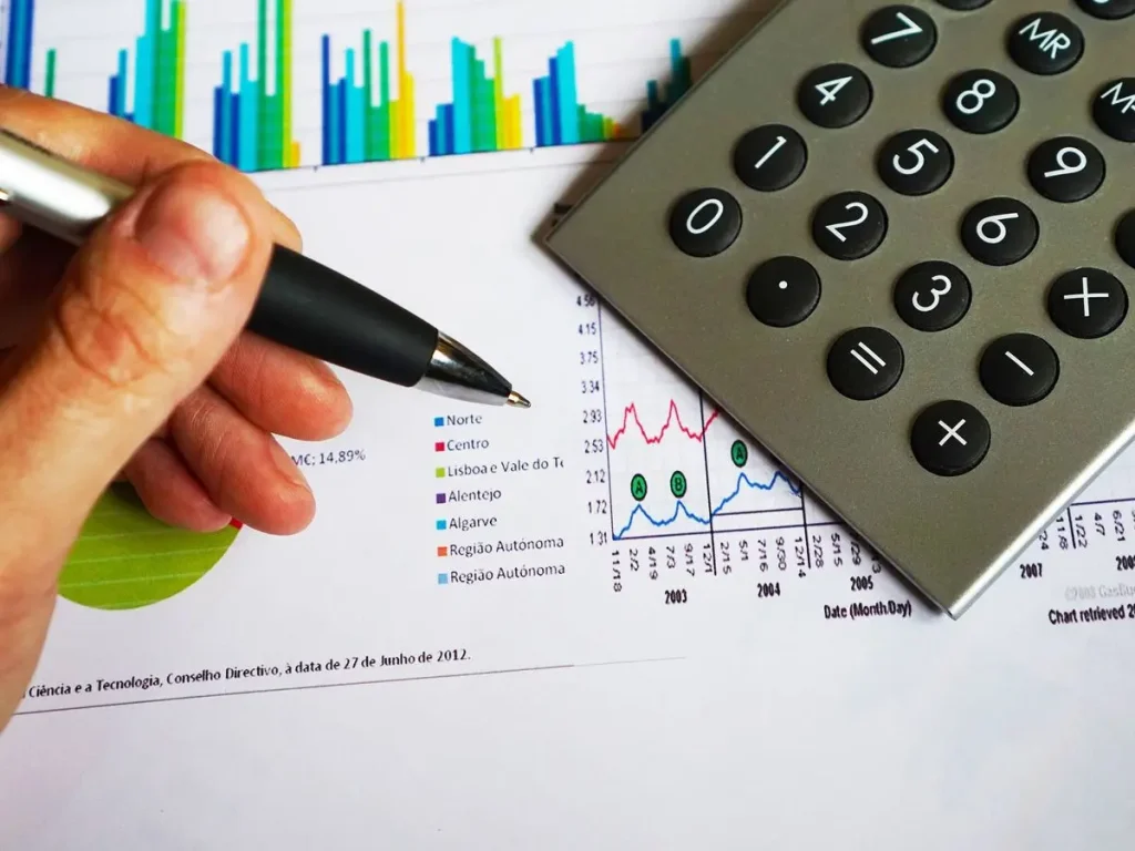 Persona señalando un gráfico financiero con una calculadora al lado, representando la gestión sencilla del dinero diario con aplicaciones