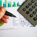 Persona señalando un gráfico financiero con una calculadora al lado, representando la gestión sencilla del dinero diario con aplicaciones