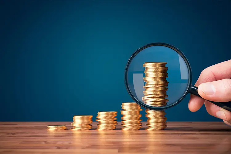 Lupa examinando una pila creciente de monedas, representando el análisis de ingresos irregulares de los creadores digitales