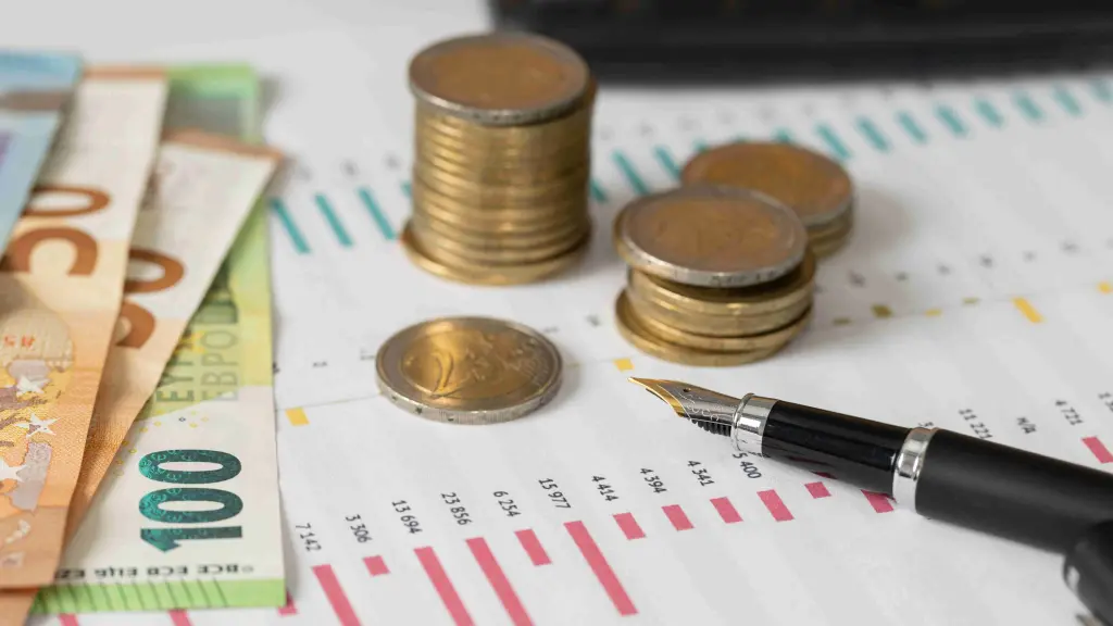 Monedas y billetes de euro sobre un gráfico financiero junto a una pluma, representando los límites dinámicos del presupuesto
