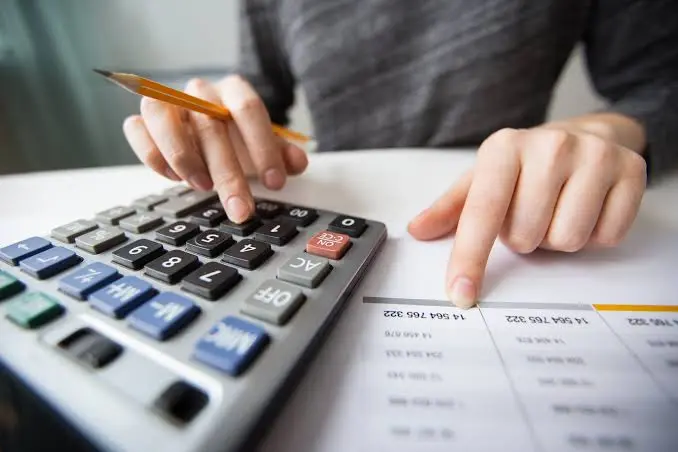 Persona usando una calculadora junto a un documento con cifras financieras, representando la organización de las finanzas personales con herramientas de gestión